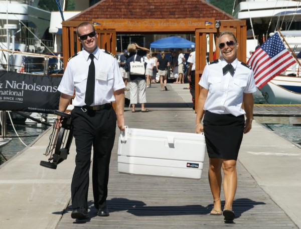 Superyacht crewmembers walking up the dock at a yacht show.